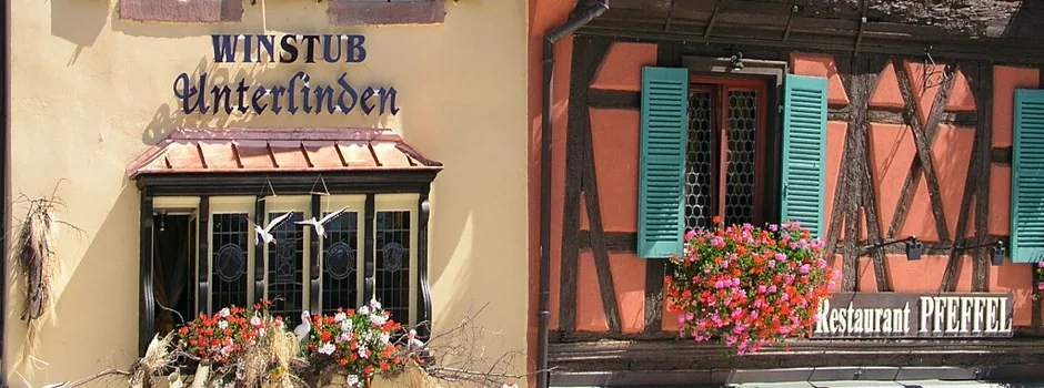 La façade du restaurant Pfeffel : colombages, volets turquoise et géraniums
